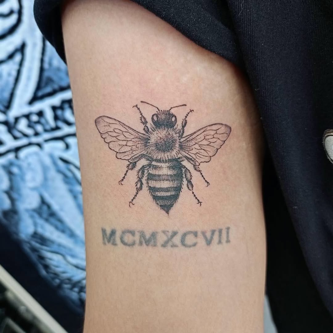Bee Tattoo β Detailed Black & Grey Insect Tattoo A detailed black and grey bee tattoo with textured wings, realistic body markings and fine stippled s